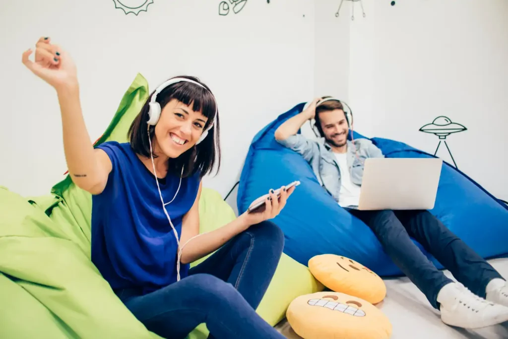 Two friends relaxing together, listening to music with Spotify premium familythrough shared headphones.
