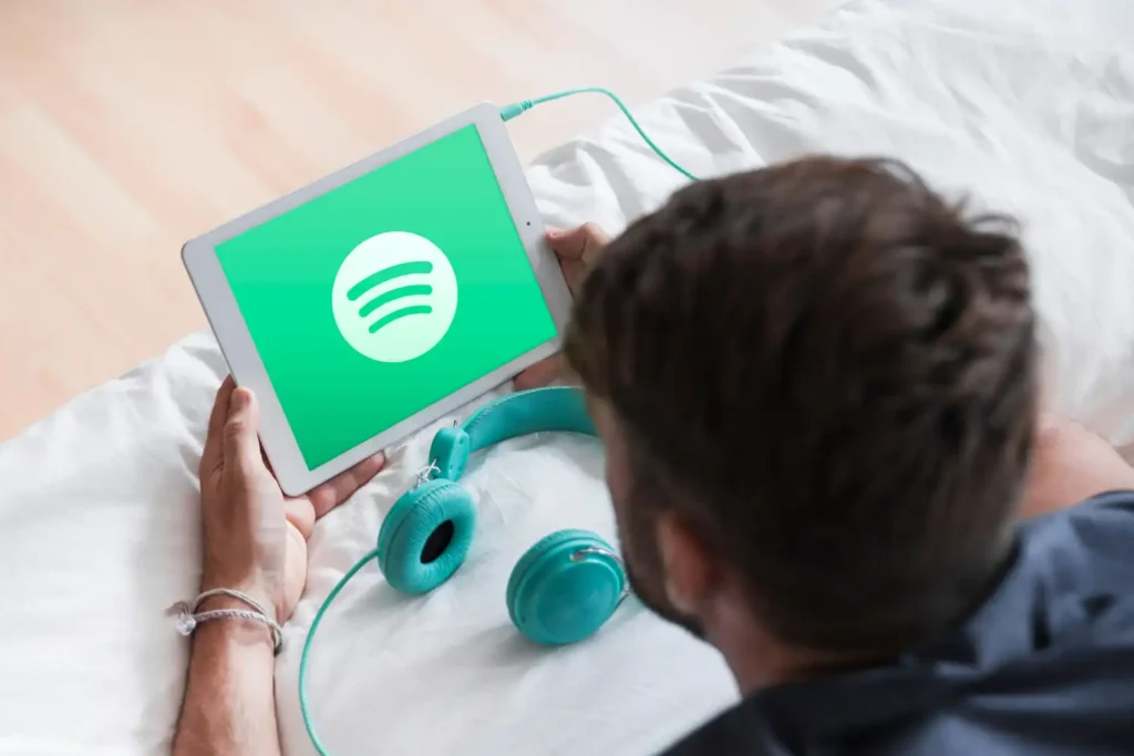 Young man using a tablet to browse Spotify, enjoying music streaming.