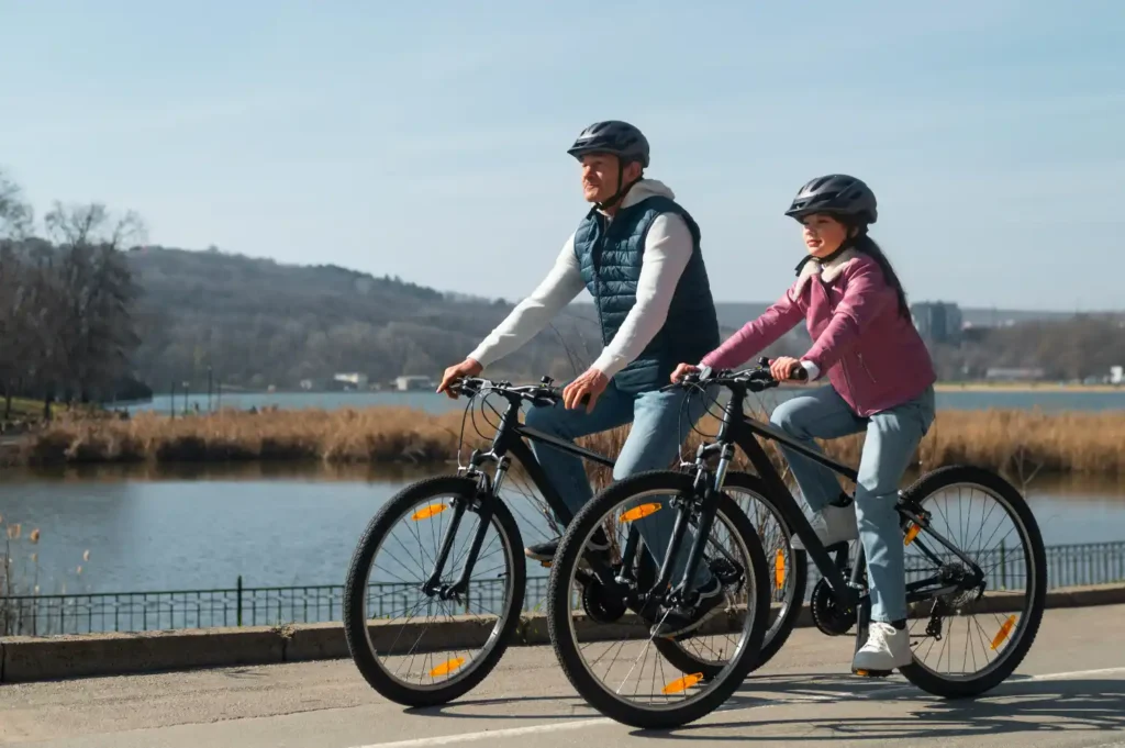 Padre e figlia che pedalano insieme su una bicicletta elettrica, sorridendo e godendosi il momento all'aria aperta.