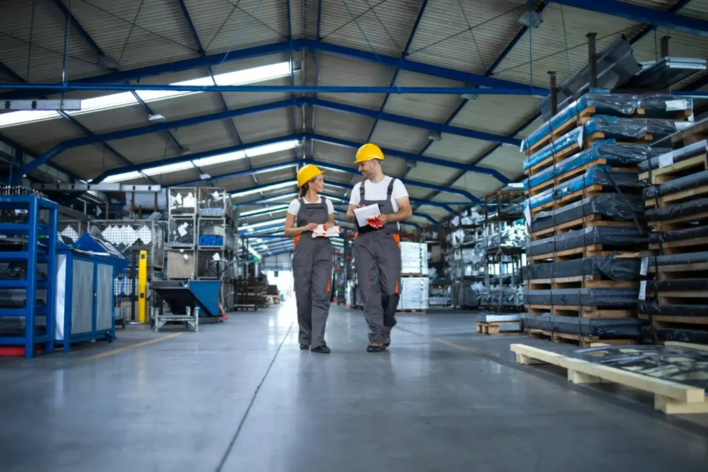Due lavoratori di un'industria a lavoro: Operai collaborano in un ambiente industriale tecnologico, integrando sostenibilità e innovazione.