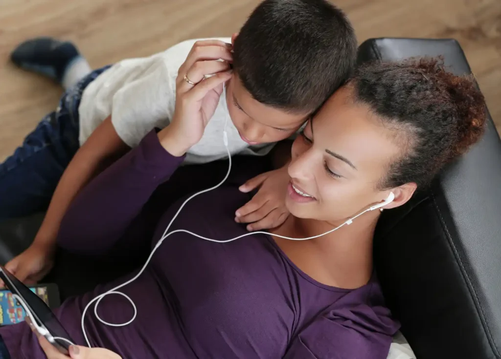 Mother and child spending time togetherusing Spotify premium family on her smartphone.