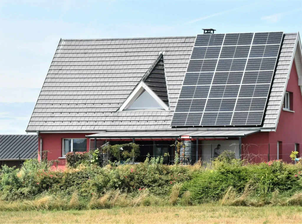 Dettaglio di un pannello solare installato su un tetto di casa con un dispositivo di accumulo accanto, per una gestione sostenibile dell'energia.