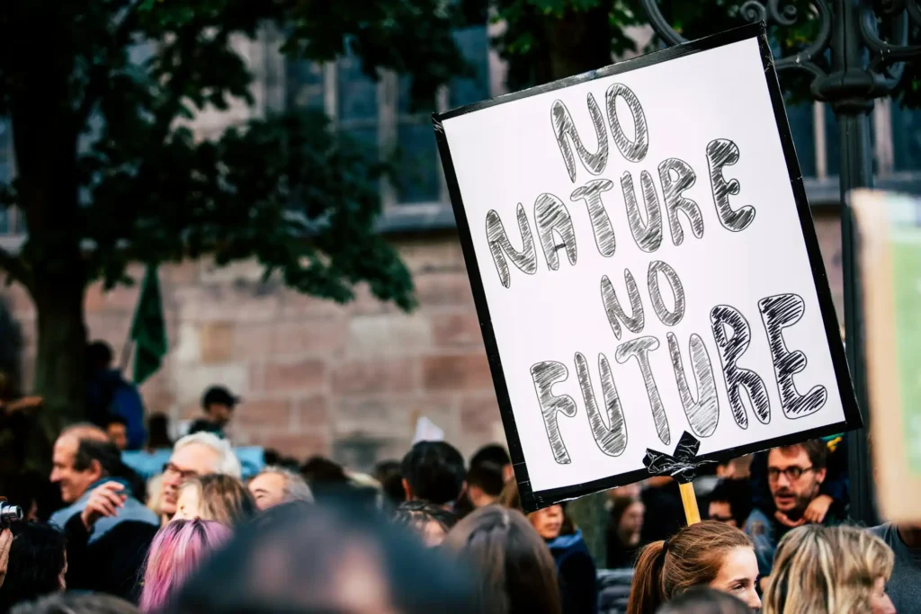 Persone di diverse età e background che protestano con cartelli colorati e messaggi di speranza e azione urgente per affrontare la crisi climatica.