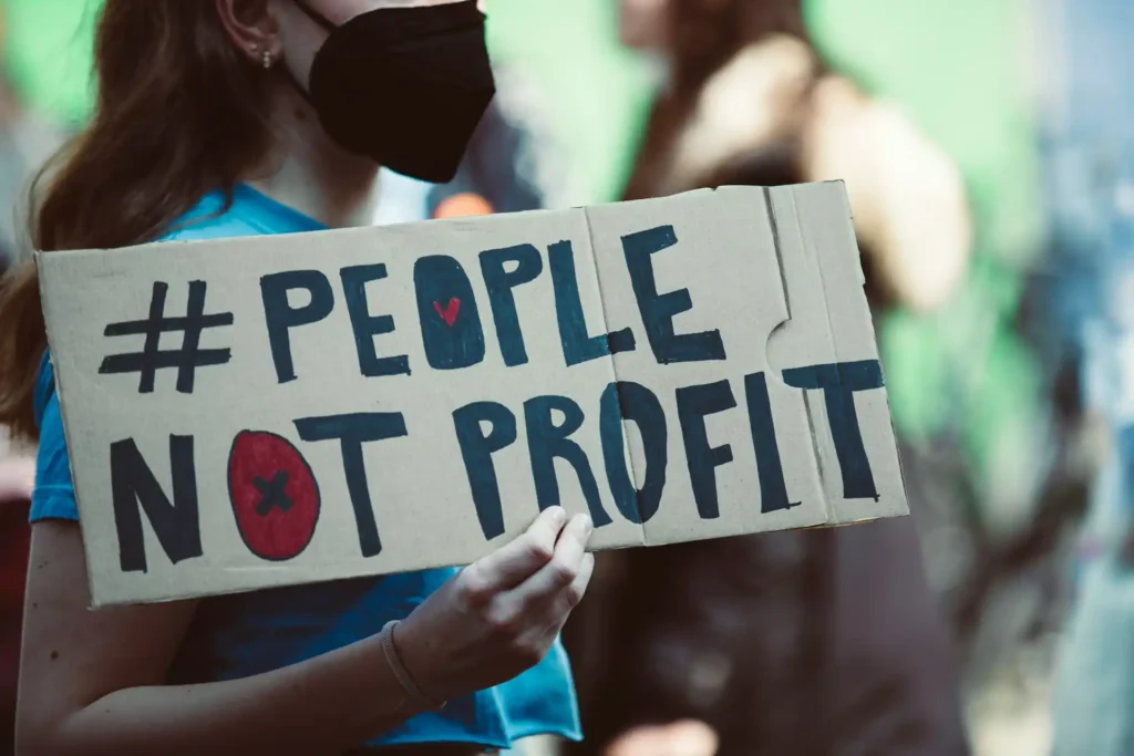 Una manifestazione vivace con persone in piedi su una strada, con cartelli di protesta e bandiere che chiedono cambiamenti nelle politiche climatiche globali.