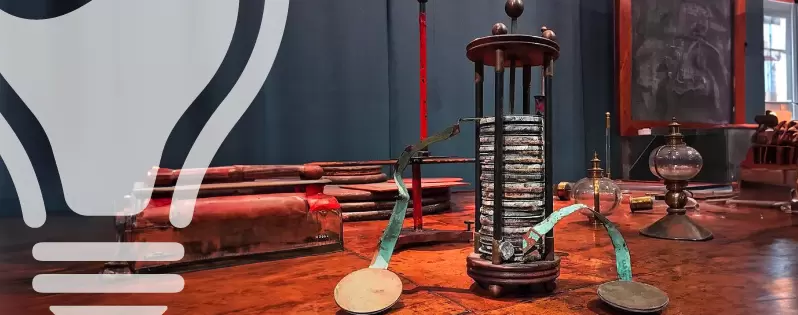 Una pila voltaica ricostruita, composta da dischi alternati di rame e zinco separati da cartone imbevuto in soluzione salina, disposta verticalmente. Lo sfondo è neutro per mettere in evidenza l'invenzione.
